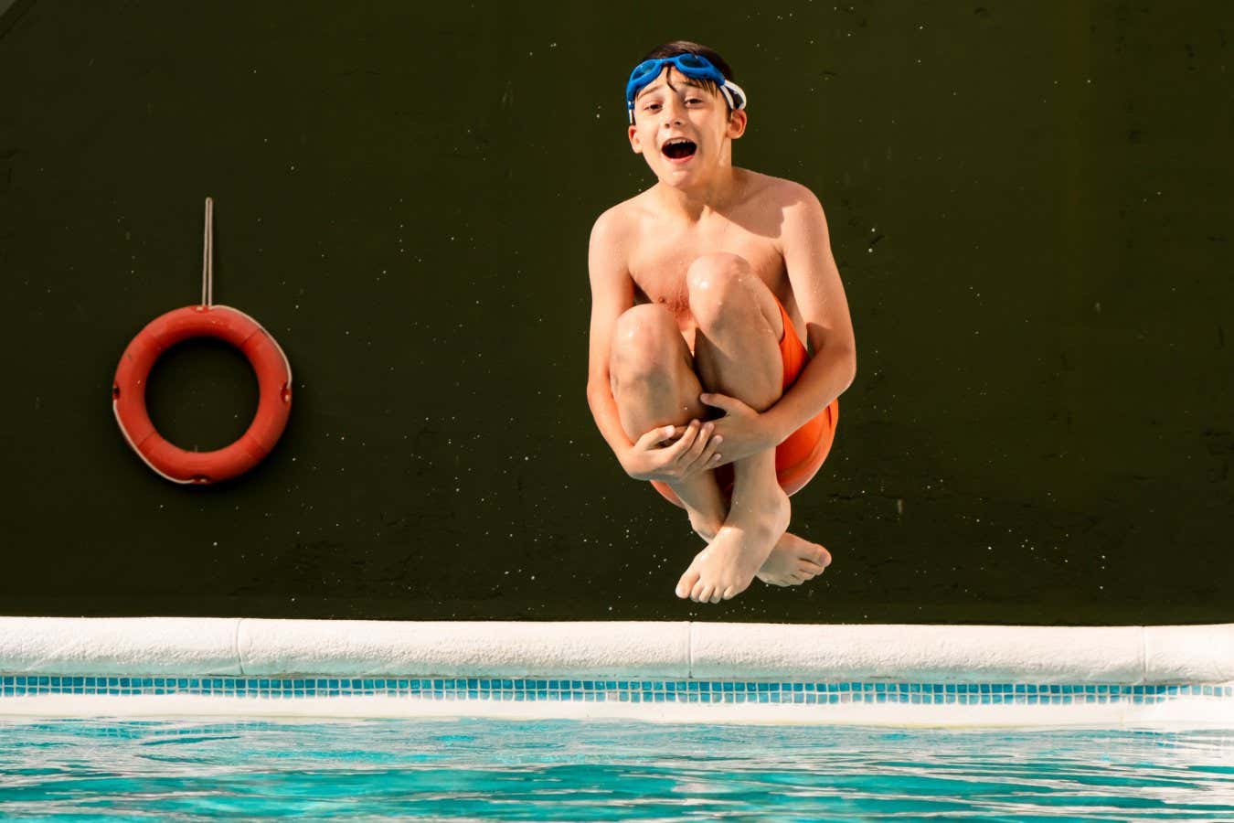 A boy jumping into a pool